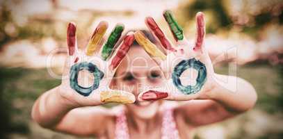 Little girl making a triangle with her painted hands to the camera