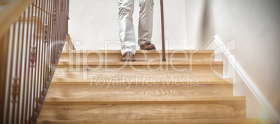 Senior man climbing downstairs with walking stick