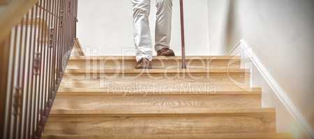 Senior man climbing downstairs with walking stick