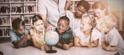 Teacher and students looking at globe in library