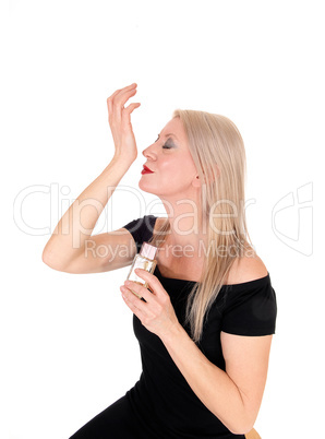 Beautiful blond woman smelling her perfume