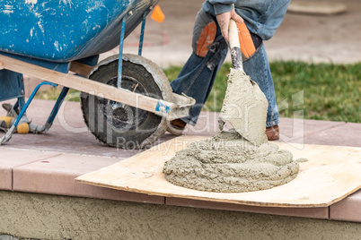 Construction Worker Placing Wet Cement On Board At Pool Site