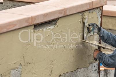 Tile Worker Applying Cement with Trowel at Pool Construction Site