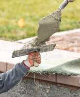 Construction Worker Placing Wet Cement On Platter For Tile Worker
