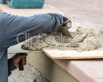 Tile Worker Mixing Wet Cement On Board At Pool Construction Site