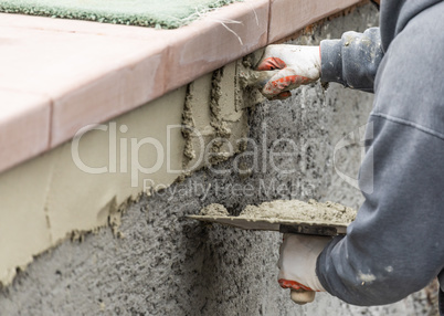 Tile Worker Applying Cement with Trowel at Pool Construction Site