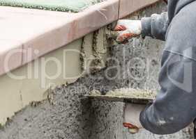 Tile Worker Applying Cement with Trowel at Pool Construction Site