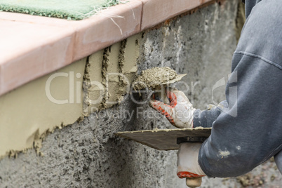 Tile Worker Applying Cement with Trowel at Pool Construction Sit