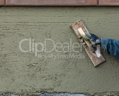 Worker Smoothing Cement with Wooden Float At Construction Site