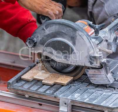 Worker Using Wet Tile Saw to Cut Wall Tile At Construction Site