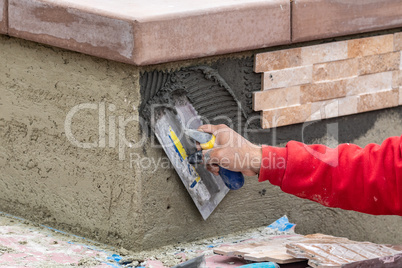 Worker Installing Wall Tile Cement with Trowel and Tile