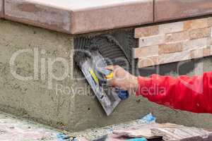 Worker Installing Wall Tile Cement with Trowel and Tile