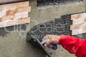 Worker Installing Wall Tile Cement with Trowel and Tile at Job Site