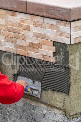 Worker Installing Wall Tile Cement with Trowel and Tile