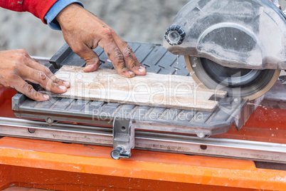 Worker Using Wet Tile Saw to Cut Wall Tile At Construction Site