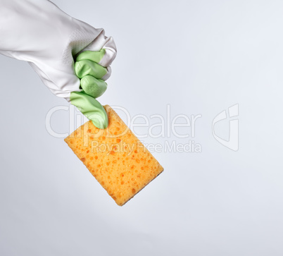 gloved hand holds yellow kitchen sponge