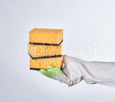 gloved hand holds yellow kitchen sponge