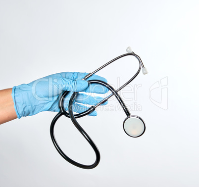 blue sterile gloved hand holding a green  stethoscope