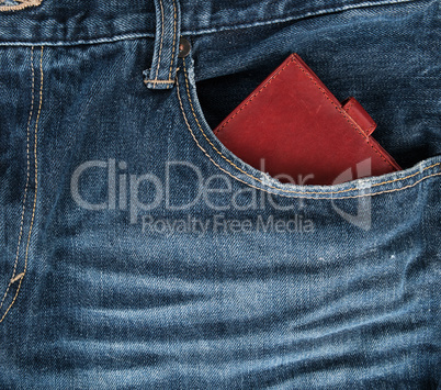 Brown leather wallet in the front pocket of blue jeans
