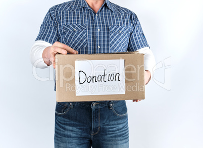 man in casual clothes holding a brown paper box with the inscrip