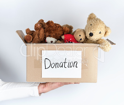 male hand holding a paper brown box with children's toys