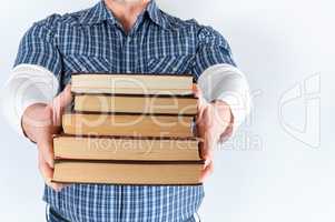 man in blue plaid shirt holding a stack of books