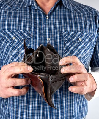 man in blue plaid shirt holds open empty leather wallet