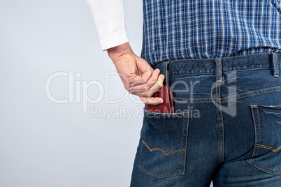 man in blue jeans and a plaid shirt shoves a leather brown walle