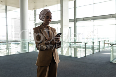 Mixed-race businesswoman using mobile phone in office lobby