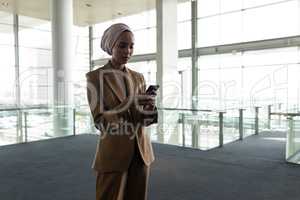 Mixed-race businesswoman using mobile phone in office lobby