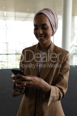 Mixed-race businesswoman using mobile phone in office lobby