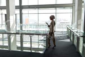 Side view of businesswoman using mobile phone in office lobby
