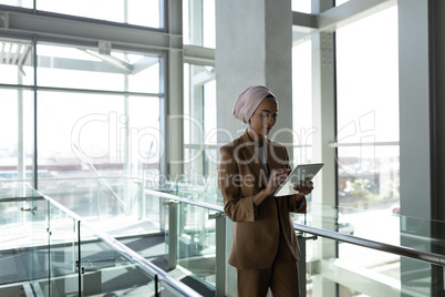Front view of businesswoman using digital tablet in office and walking on a walkway