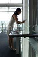 Businesswoman leaned on the railing and chating on his mobile phone on first floor walkway
