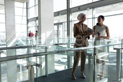 Front view of two businesswoman laughing and discussing together on first floor  walkway of the offi