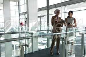 Front view of two businesswoman laughing and discussing together on first floor  walkway of the offi