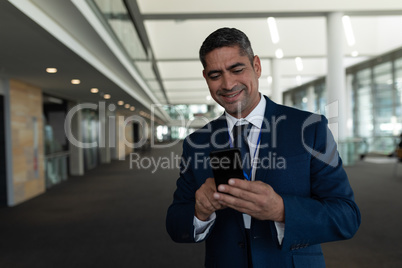 Front view of businessman laughing in using his mobile phone in office lobby