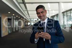 Front view of businessman laughing in using his mobile phone in office lobby