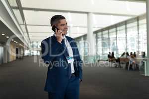 Businessman calling someone on mobile phone and looking away in office lobby