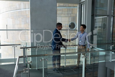 Handshake between an Asian businessman and a Caucasian businessman on the walkway of the first floor