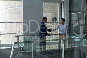 Handshake between an Asian businessman and a Caucasian businessman on the walkway of the first floor