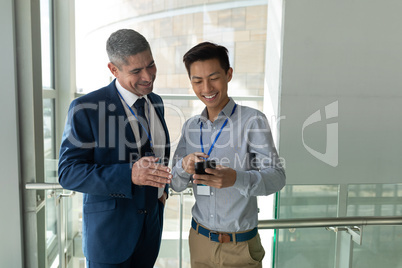 Caucasian businessman discussing and laughing with an Asian businessman on a walkway i