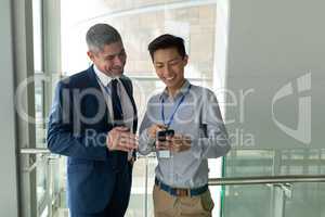 Caucasian businessman discussing and laughing with an Asian businessman on a walkway i