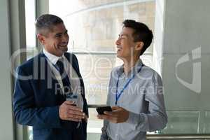 Front view of two businessman looking at themselves and laughing together in office