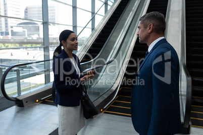 Businessman and businesswoman interacting with each other near escalator