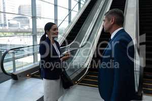 Businessman and businesswoman interacting with each other near escalator