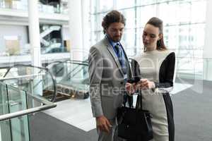 Caucasian businessman and Caucasian businesswoman discussing over mobile phone near escalator