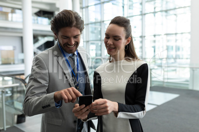 Caucasian businessman and Caucasian businesswoman discussing over mobile phone near escalator