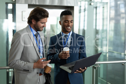 Multi-ethnic businessmen discussing over laptop near elevator