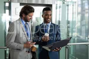 Multi-ethnic businessmen discussing over laptop near elevator